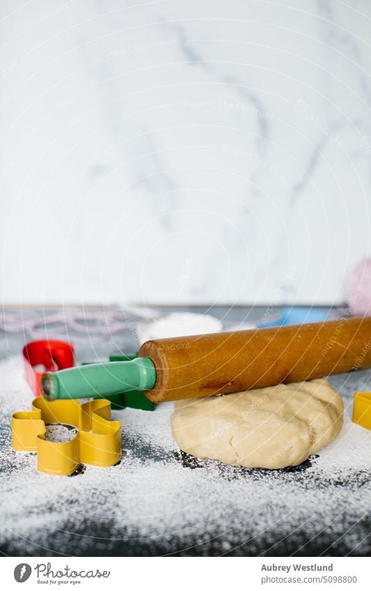 rolling pin sitting on ball of cookie dough surrounded by Christmas cookie cutters bake baking sheet black candy cane celebration childhood children christmas