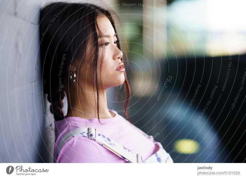 Asian woman leaning on wall calm street urban style melancholy modern personality female young asian ethnic braid depression alone peaceful feminine daytime