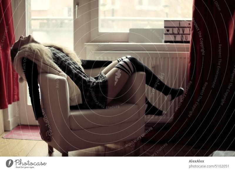 Portrait of young blonde woman lying in armchair at an angle and laughing portrait Woman Young woman Balcony French windows Armchair Legs Sock Dress Blonde