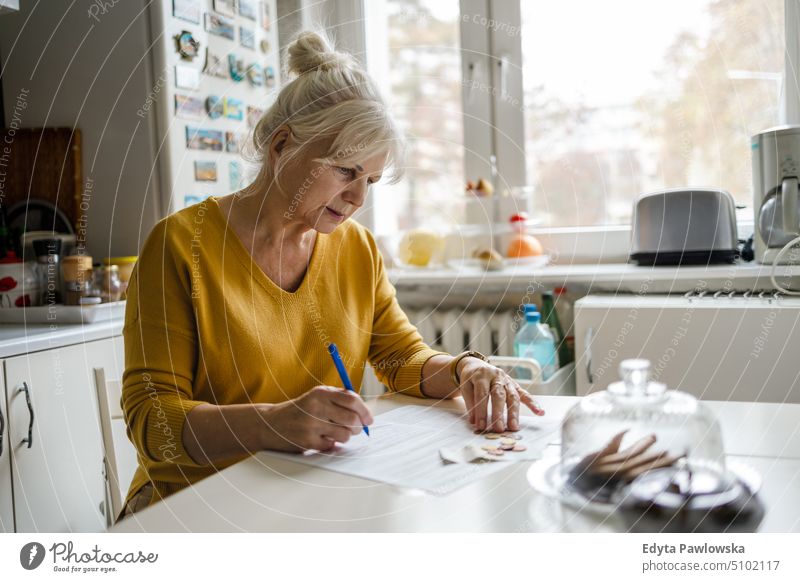 Senior woman filling out financial statements people senior mature female elderly home house old aging domestic life grandmother pensioner retired retirement