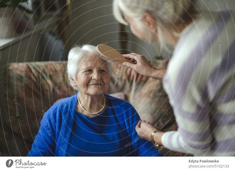 Woman combing hair of elderly mother smiling happy enjoying positive people woman senior mature female home house old aging domestic life grandmother pensioner