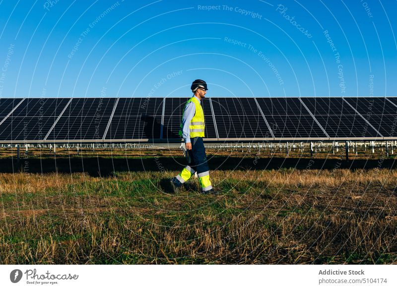 Technician passing by photovoltaic cells in field man technician solar panel sustainable alternative eco friendly energy renewal male professional countryside