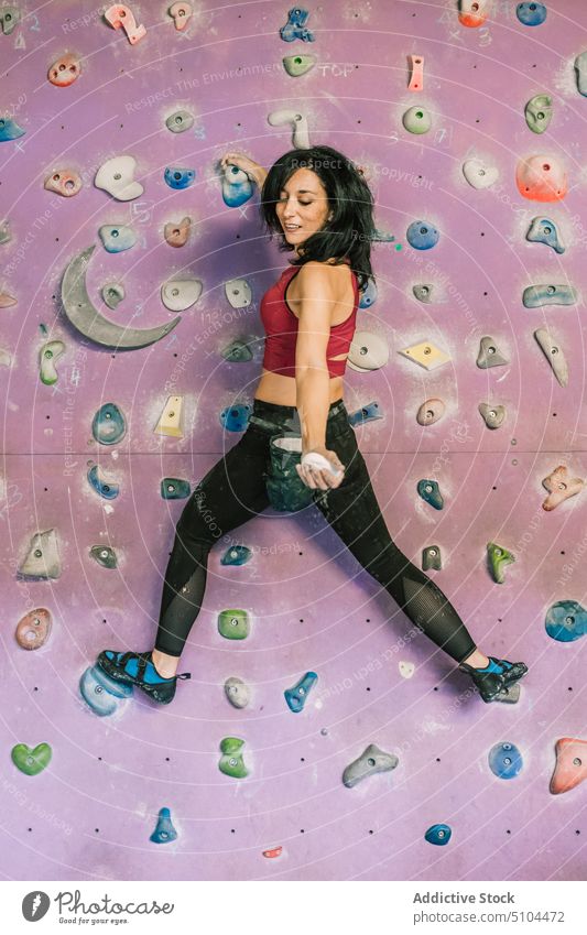 Sportswoman with chalk hanging on climbing wall sportswoman bouldering gym climber training extreme female strong effort strength brave hobby courage workout