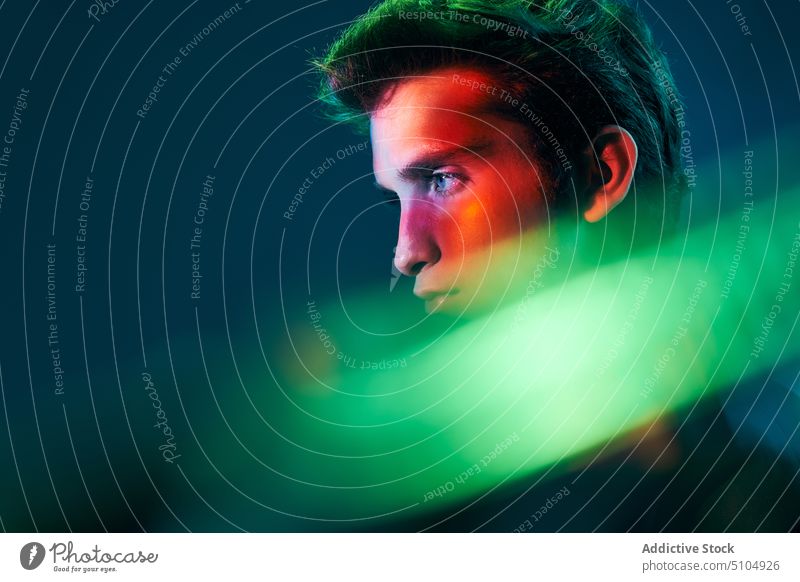 Young man profile in neon illumination model portrait multicolored light studio shot individuality emotionless unemotional male young luminous lightning bright