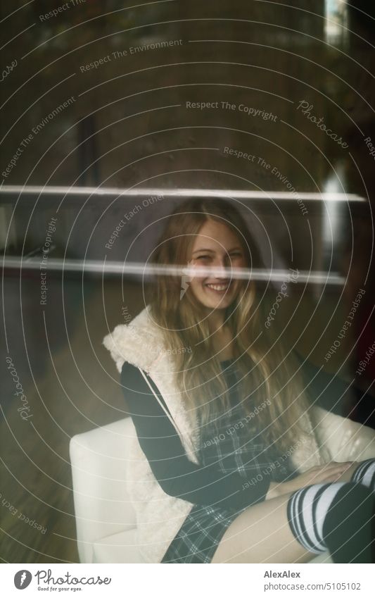 Portrait through balcony door of young blonde woman sitting diagonally in armchair portrait Woman Young woman Balcony French windows Armchair Legs Sock Dress