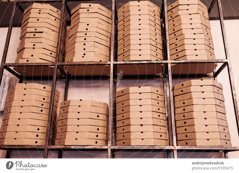 food delivery service. tall stacks of flat brown cardboard pizza boxes on metal shelf ready for delivery. craft packing boxes with pizza in stock in storage