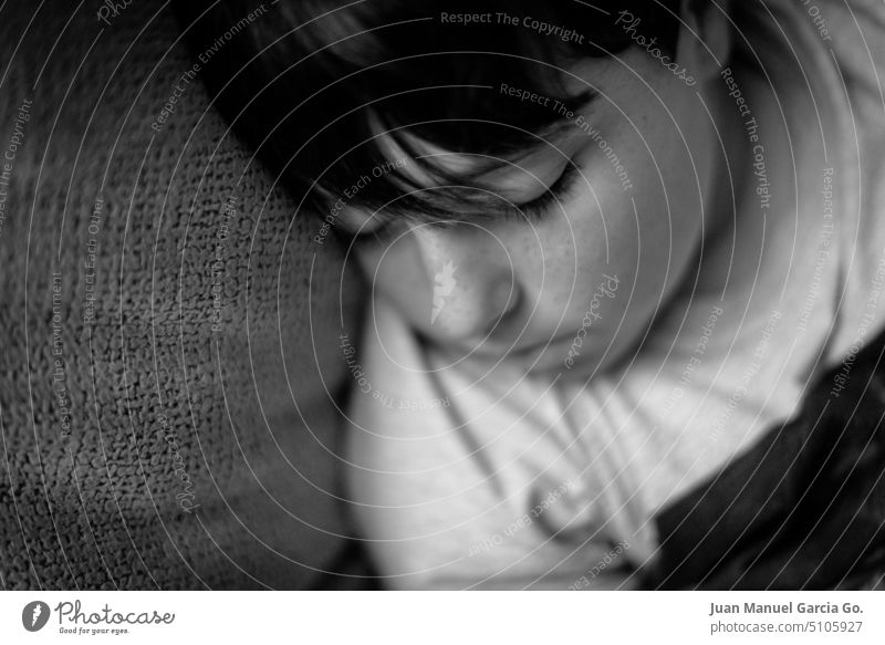 Close-up of boy with bangs asleep on the armchair, black and white image with selective focus atmosphere avoid back busy day child close-up common situation