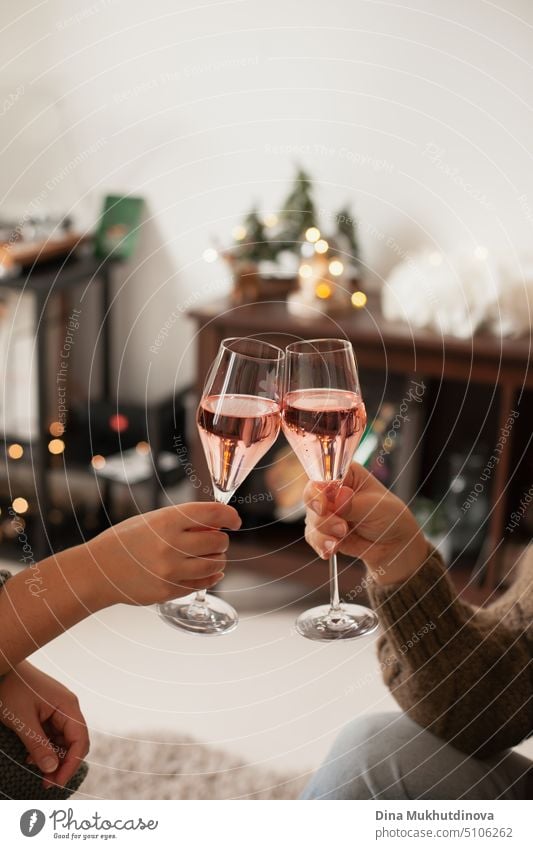 Holding two glasses of rose sparkling wine to cheers for Christmas or New year. Celebrating at party. Happy Birthday or anniversary. Festive drinks background