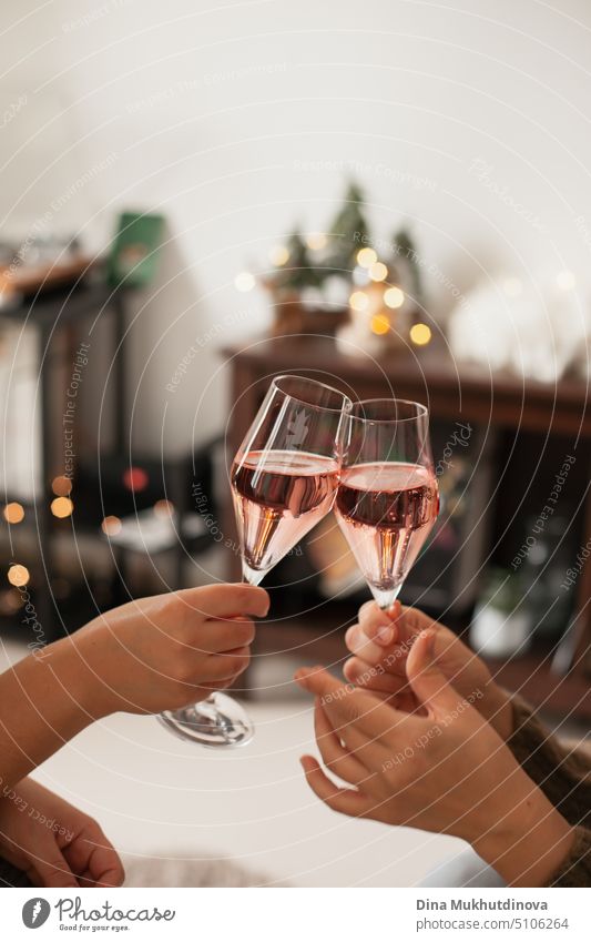 Holding two glasses of rose sparkling wine to cheers for Christmas or New year. Celebrating at party. Happy Birthday or anniversary. Festive drinks background