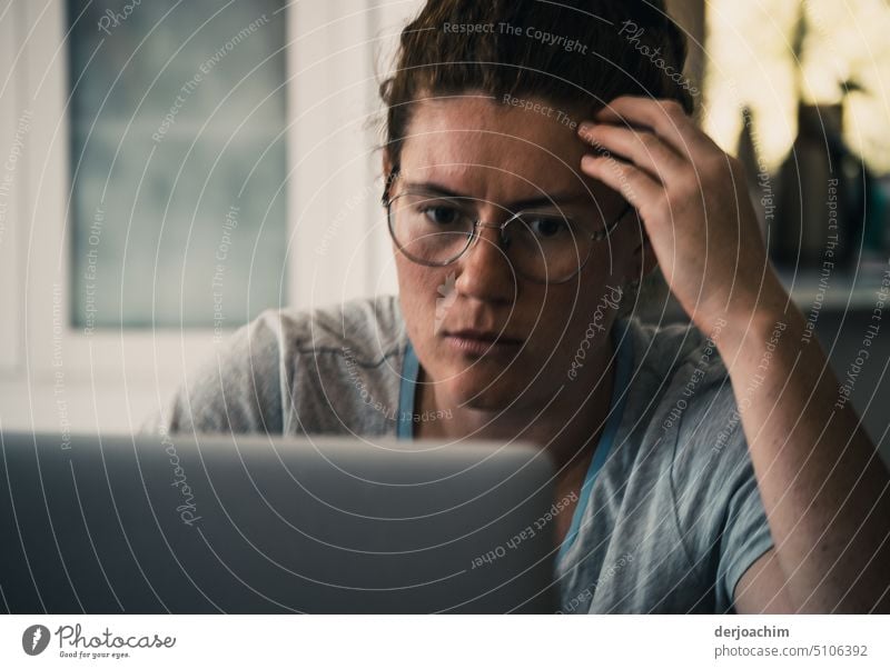 Young woman with glasses sits in front of a PC and grabs her head with her fingers. pc Computer Screen work Home Woman Internet Technology Office youthful