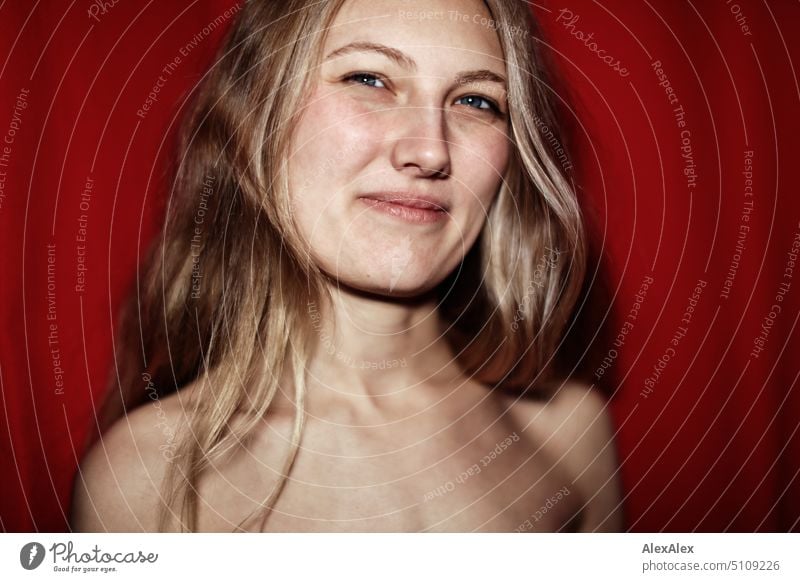 Close portrait of young blonde woman smiling in front of red background Woman Young woman Blonde Long-haired Smiling Joy Slim kind Pleasant pretty Attractive