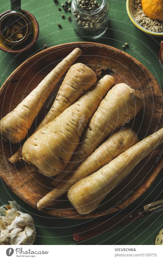 Raw parsnip vegetables on wooden plate , top view raw parsley vegetarian food background healthy root