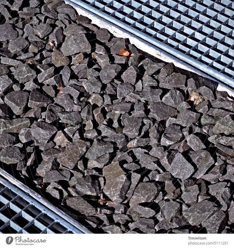 Material mix in the square Grating Metal gravel stones Light Shadow Exterior shot Deserted Colour photo rough edges Detail