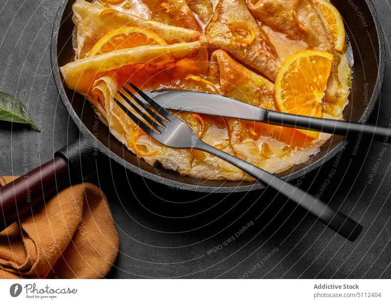 Homemade crepes suzette with orange liqueur and orange slice pan served concrete orange liquor cointreau fork and knife european sugar copy space pancakes hot