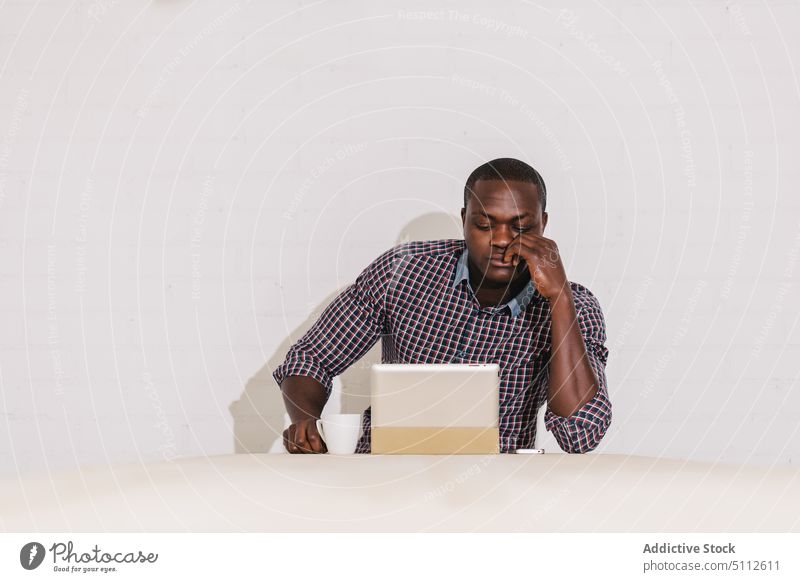 Pensive Black Man Working with a Digital Tablet on a Wooden Table office business male businessman happy adult handsome wireless confident people tablet black