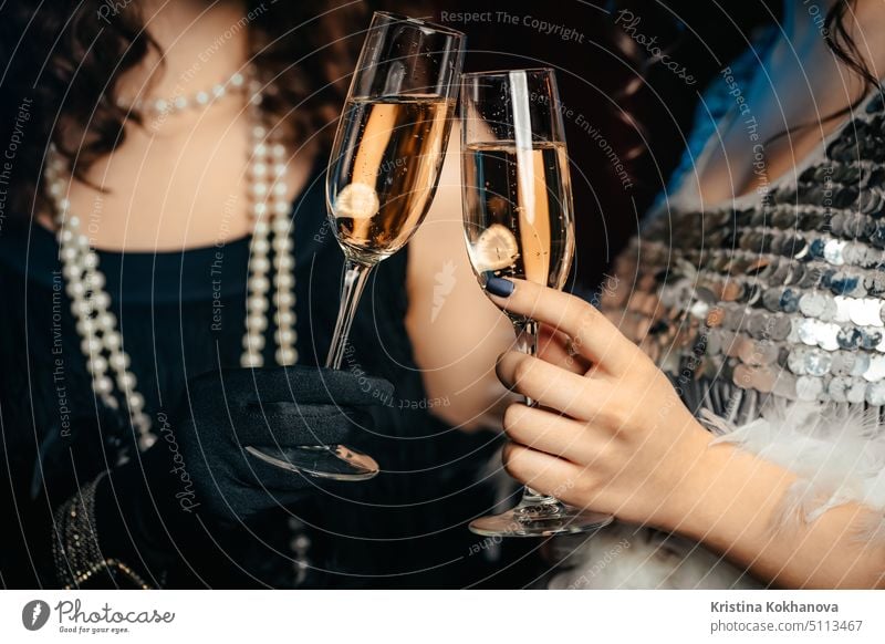 Close up glasses of champagne. Flappers women wearing in style of Roaring Gatsby twenties drinking alcohol. Vintage, retro party, fashion, girls friends concept