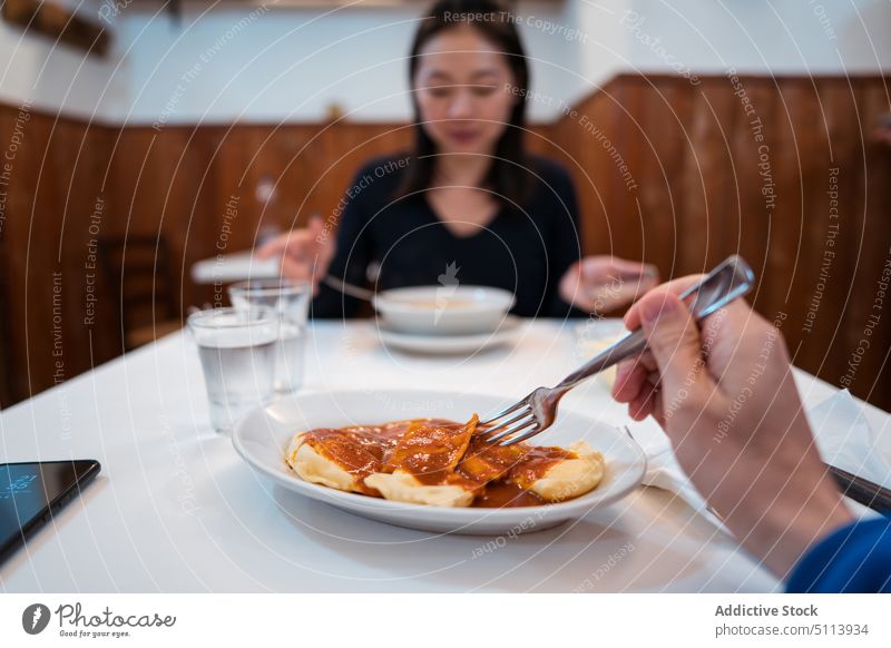 Young Asian lady eating soup during dinner with crop man woman hungry restaurant couple food dish together yummy female young asian ethnic brunette casual