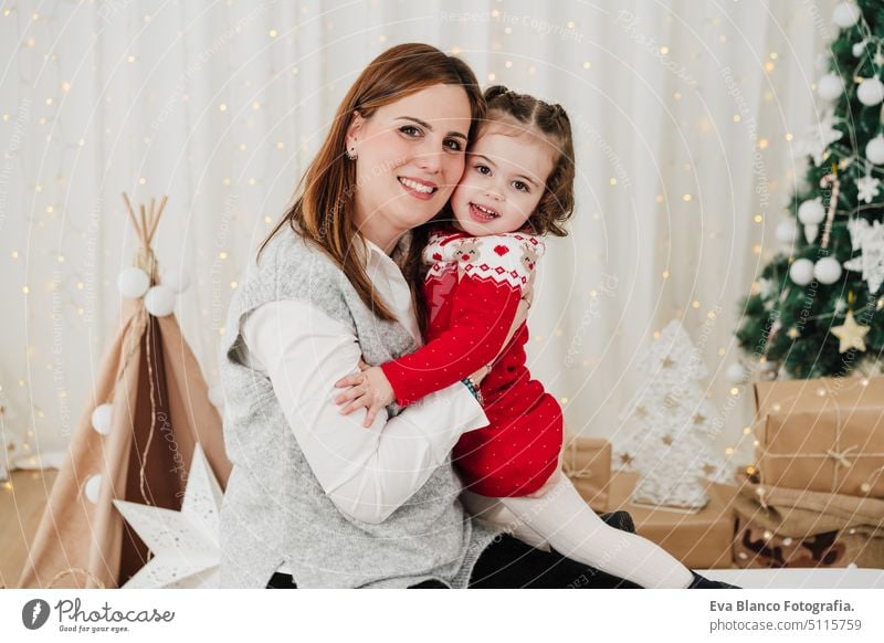 happy mother and daughter embracing at home during christmas time family living room love together motherhood single mother caucasian celebration child indoors