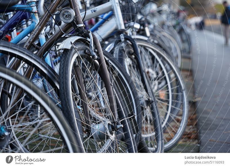 Bicycles parked on a busy street near footpath in Lucerne. Focus is in the middle of picture on wheel of one bike, where foreground and background are defocused.