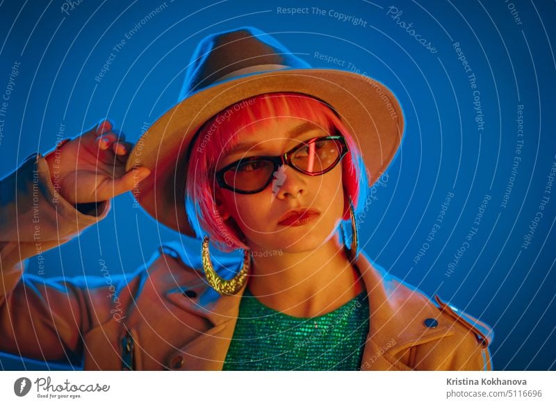 Portrait of glamorous woman on party under glowing neon light. Nightclub, trendy outfit. Teenager, zoomer Z-generation. Lady in hat and glasses. african dancing