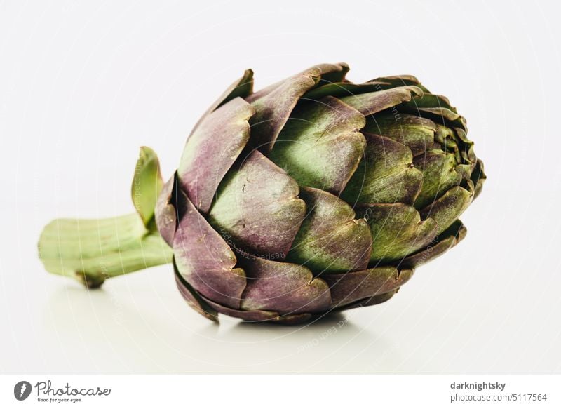 A ripe artichoke lies on a light background Artichoke Still Life Nutrition Vegetarian diet Food Vegetable Raw Healthy Green Colour photo Fresh Diet Violet