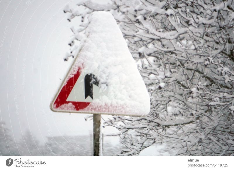 Traffic sign - Attention winding road - in flake swirl and partly covered with snow / winter Road sign street sign Caution winding road double curve StVO