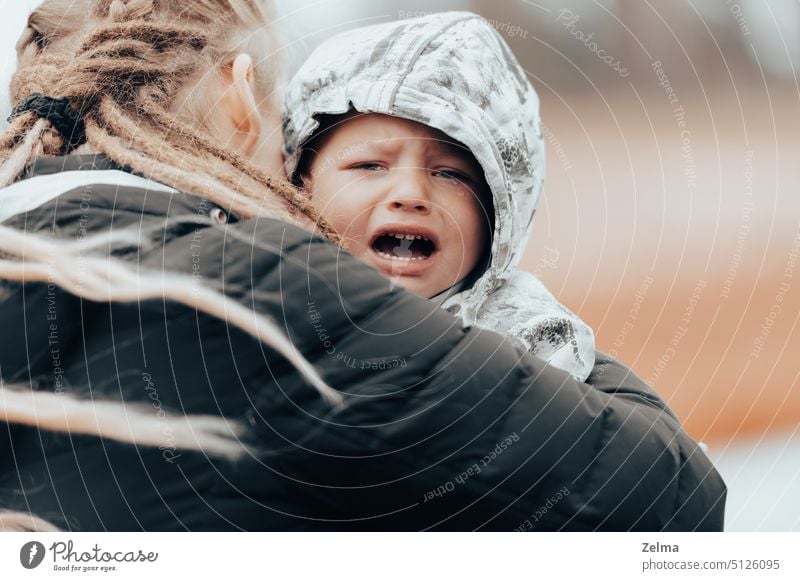 Mother holding crying baby, sad little boy being hugged by his mother mom son child kid embracing emotional stress facial expression sadness tears family