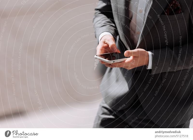 Closeup shot of an unrecognisable businessman in suit is using smartphone outdoors by the office. Making moves in the corporate world. Staying on top of the latest business news. copy space