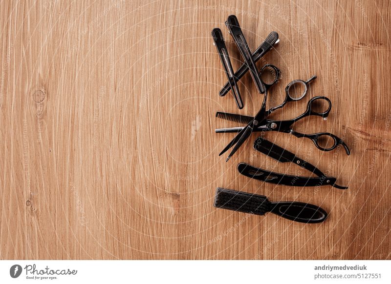 Barber shop equipment on wooden background with place for text. Flat lay composition with comb, scissors, vintage razor for shaving beard, black clothespins. Professional hairdressing tools.