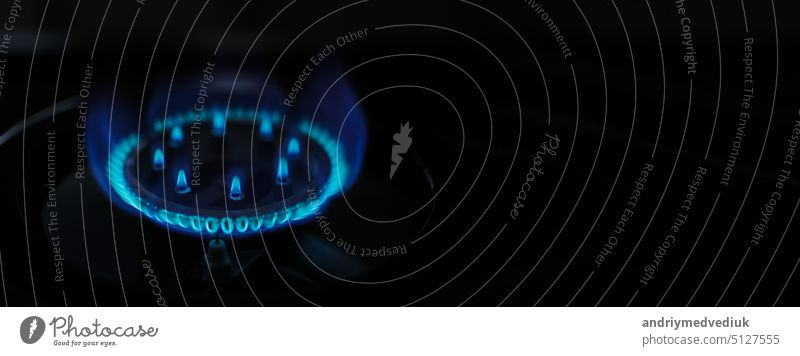 Natural gas blue fire flame on kitchen burner gas stove on dark background. Circular gas-jet. Flame Gas Burner Operation. Shortage and gas crisis. heat energy