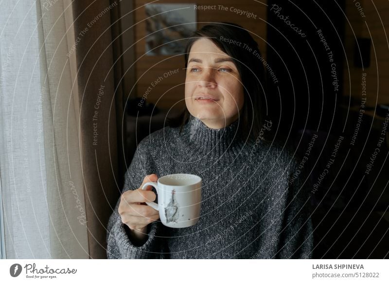 Portrait of pensive woman. Girl with cup of coffee. Female drinking tea at home by window white beverage hot mug girl female beauty people portrait person cafe