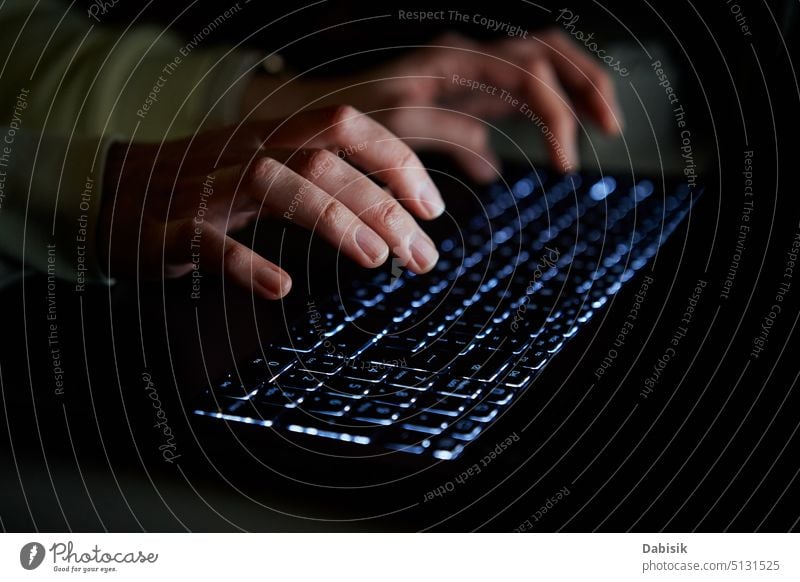 Typing on laptop keyboard at night, close up cyber security hacker typing programmer hands dark cyberattack room man person desk computer desktop background