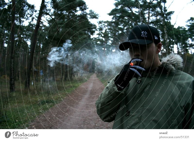 A short break on the way to happiness Cigar Cigarette Baseball cap Green Beige Forest Tree Black Gloves Exterior shot Smoking Grass Dark green Embers Recitative