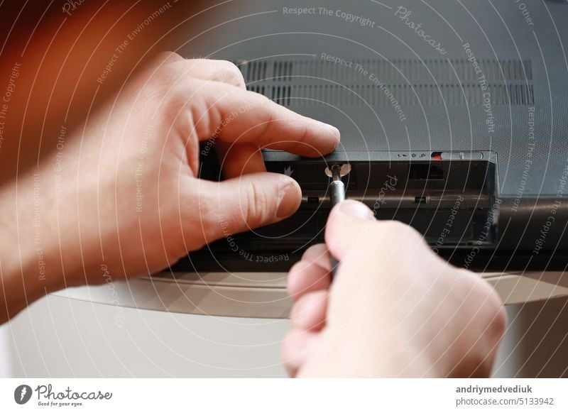 Repairman's hands unscrewing the screws from the laptop case with a screwdriver. Computer service and repair. Laptop disassembling in repair shop. Electronic development, electronic device fixing.