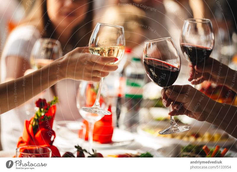 People celebrate and raise glasses of wine for toast. Group woman cheering with sparkling champagne in restaurant background celebration cheers city drink event