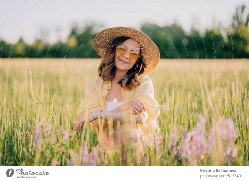 Portrait of rural stylish woman in straw hat posing in fresh wheat field. Grass background. Amazing nature, lifestyle, farmland, growing cereal plants. country