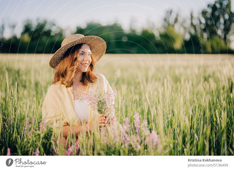 Portrait of rural stylish woman in straw hat posing in fresh wheat field. Grass background. Amazing nature, lifestyle, farmland, growing cereal plants. country