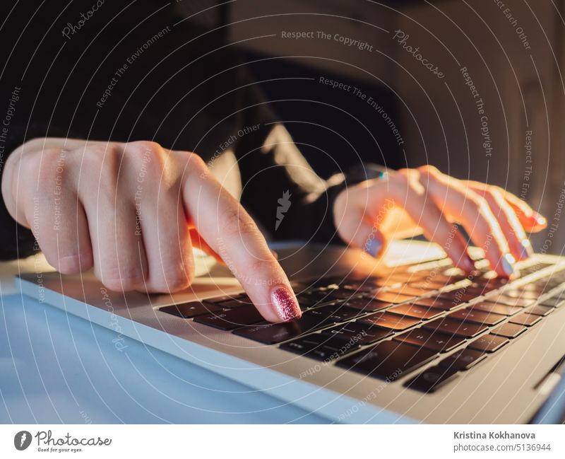 Young business woman working on laptop. Focus on hands typing on keyboard. Sunrise or sunset light leaks communication computer device female finger girl