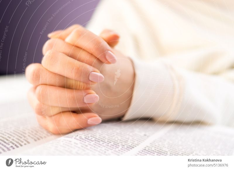 Unrecognizable woman reading big book - Holy Bible and praying. Christian studying scripture. Student in the college library preparing for exams. Learning, gratitude, religion concept.