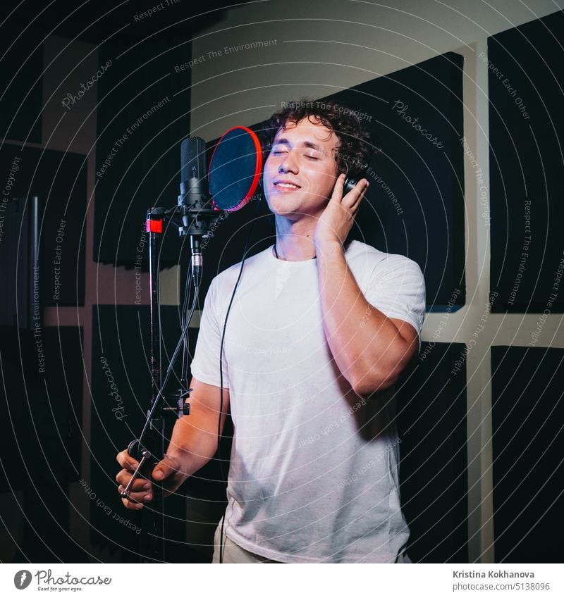 Male vocal artist with curly hair singing alone. Young handsome singer man emotionally writing song in the studio. Recording new melody or album. audio