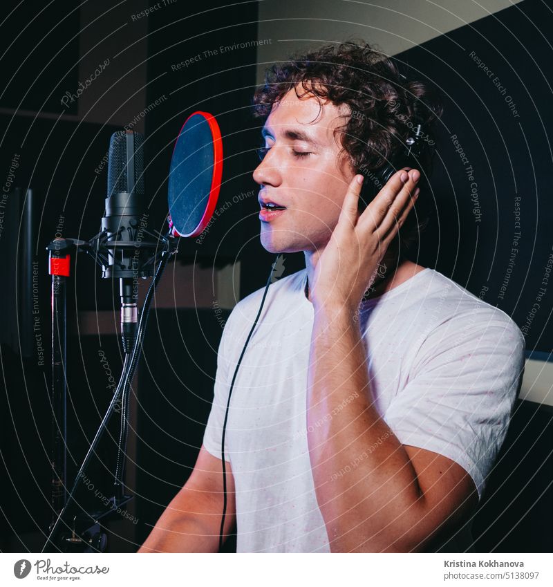 Male vocal artist with curly hair singing alone. Young handsome singer man emotionally writing song in the studio. Recording new melody or album. audio