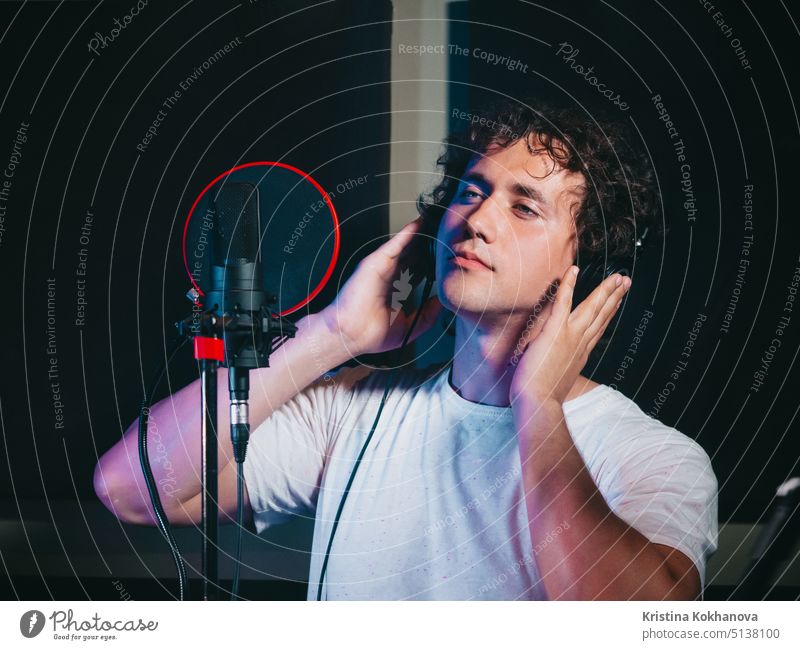 Male vocal artist with curly hair singing alone. Young handsome singer man emotionally writing song in the studio. Recording new melody or album. audio