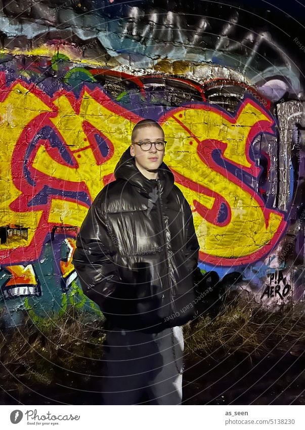 Youth in front of graffiti wall in the dark Graffiti younger Young man darkness Man Human being Exterior shot 16 years 18 - 30 years Masculine