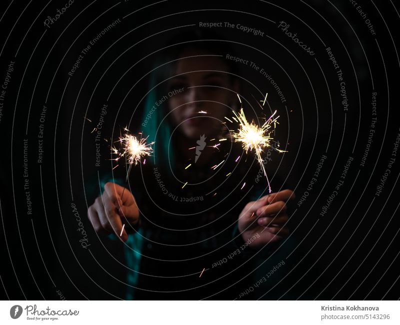 Portrait of model girl with blue hair looks with sparklers in their hands. Close up. Beautiful young teenage in city tunnel having fun with bengal fire. beach