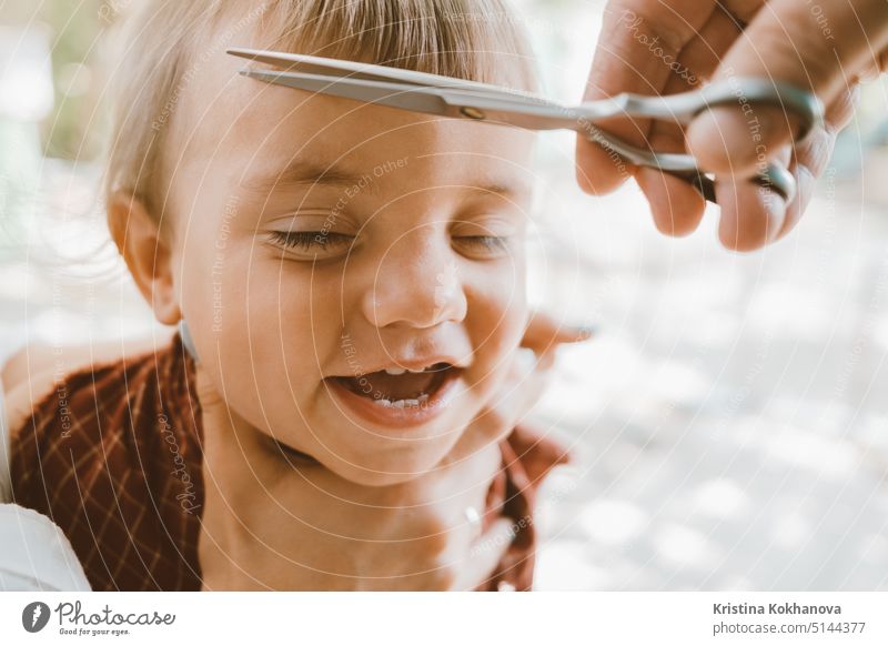 First haircut of little baby boy at home by parents. Cute funny portrait. child cute hairdresser childhood toddler face head kid adorable barber beauty