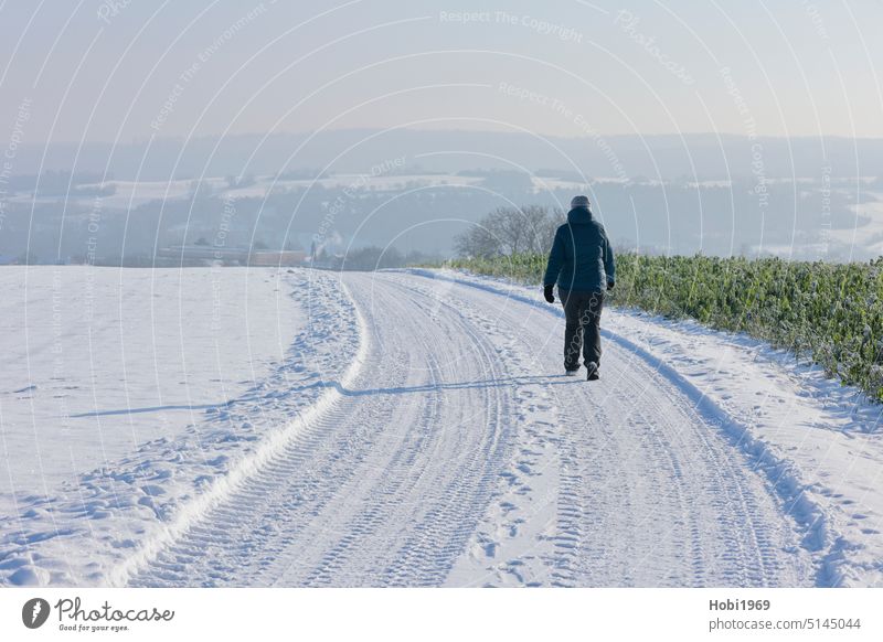 Hiker walks in winter sunshine through the Heckengäu near Weissach wanderer Winter sunny Hiking active Horizon Sky Landscape Frost Snow Sun Athletic Sports