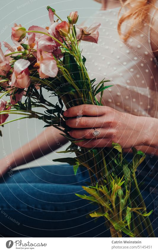 Woman with ring on finger holds flowers in hand Ring Diamond Gold Jewellery Bouquet Top Jeans points Green Pink pink flowers