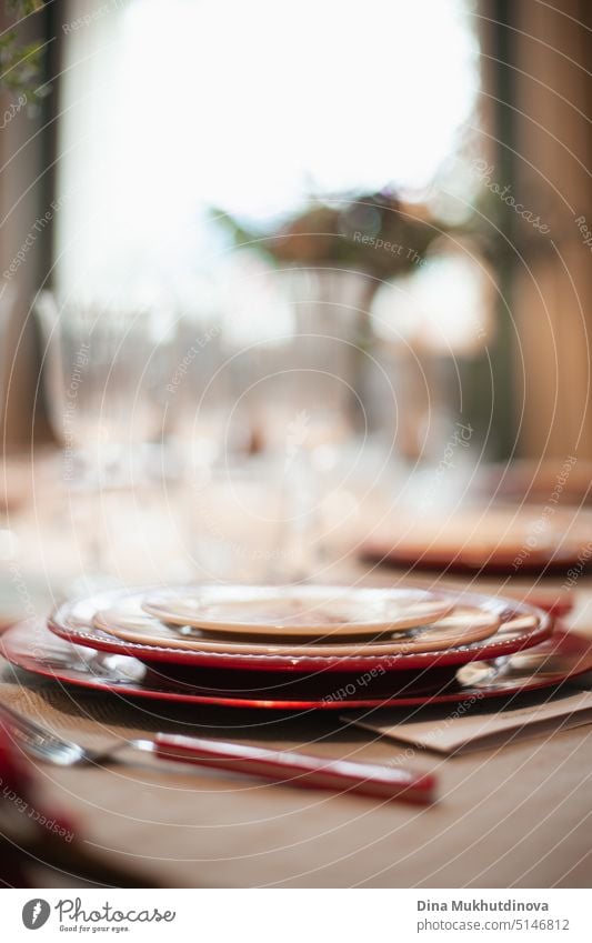 Festive christmas table setting with classic red and white color plates, tableware, glasses and candles and holiday season decor and christmas tree catering