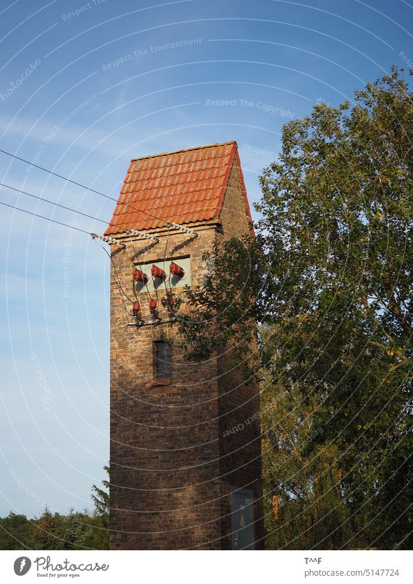 Gemauerte Turmstation mit Baum vor sommerlichem Himmel Station Transformator Trafo Isolator Isolatoren Freileitung Energie Strom Energietransport Stromtransport