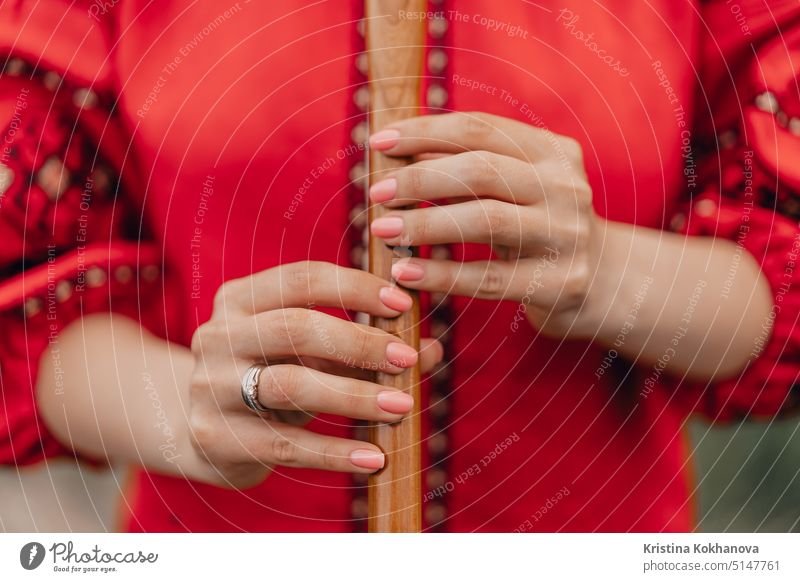 Woman playing woodwind wooden flute - ukrainian sopilka outdoors. Folk music concept. Musical instrument. Lady in traditional embroidered shirt - red Vyshyvanka.